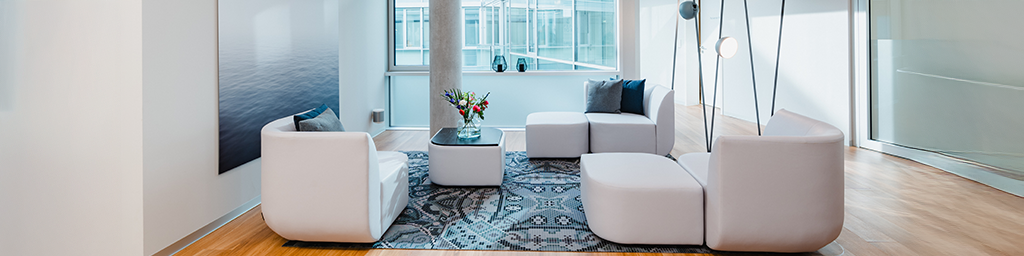 Foto von den modernen und gemütlichen Räumlichkeiten der Klinik für Plastische Chirurgie Penna Torio in Freiburg. Helle Klinikräumlichkeiten mit bequemer, moderner Sofalandschaft.